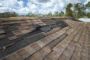 Damaged house roof with missing shingles after hurricane Ian in Florida.