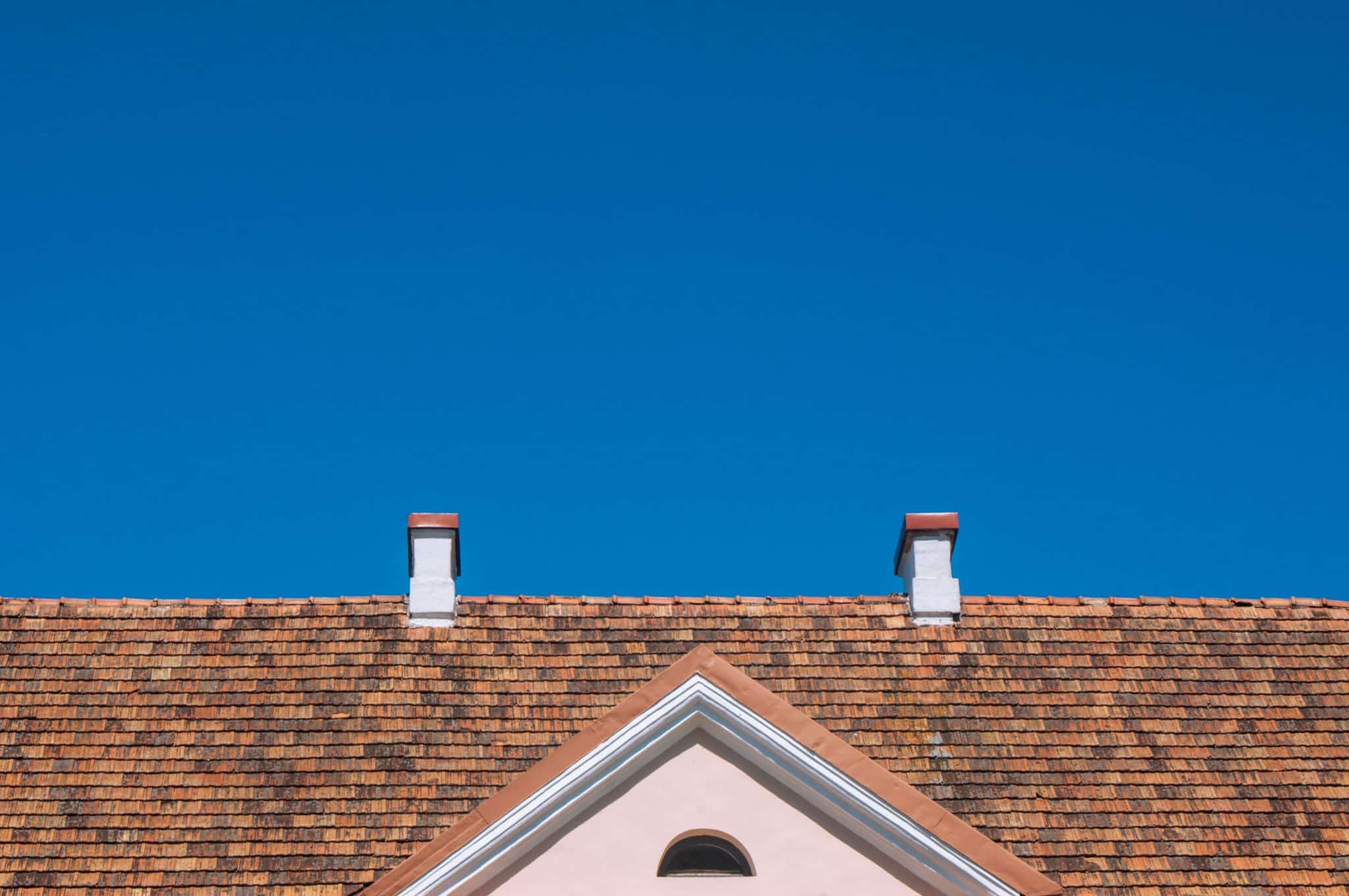 A roof of a home with the clear blue sky visible behind it